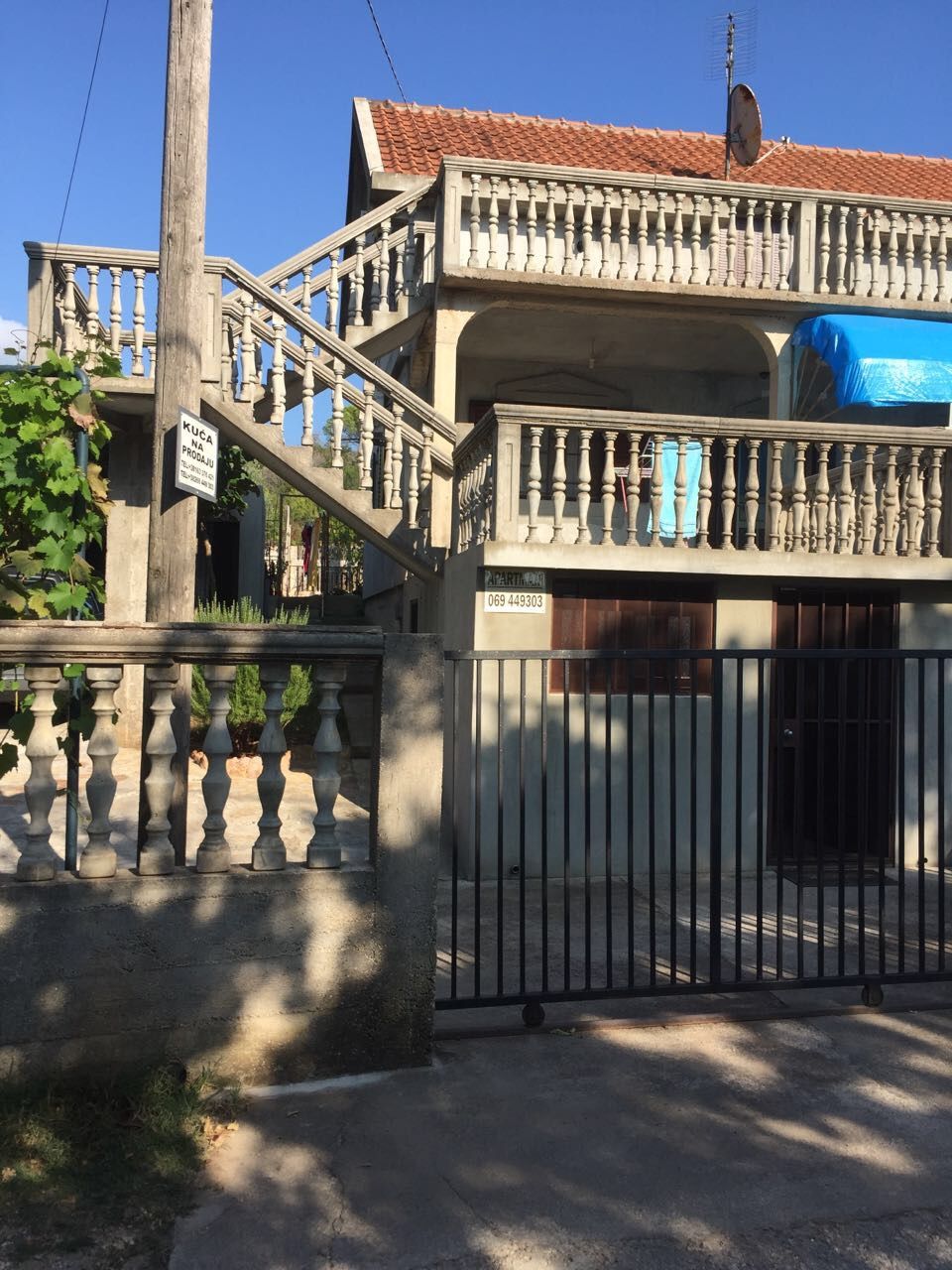 Two-story house for sale in Krimovica, Montenegro: facade with concrete balustrades, exterior staircase, and gate.