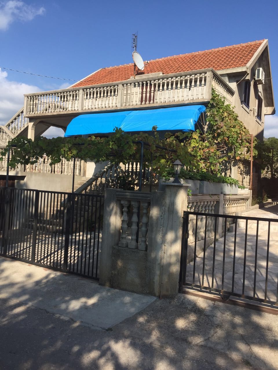 Two-story house with a terrace and grapevine in Krimovica, Montenegro: front view and entrance area with gate.