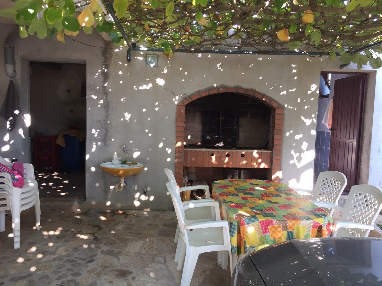 Cozy terrace with a stone barbecue and lounge area in a house, Krimovica, Montenegro. Summer kitchen under a grapevine canopy.