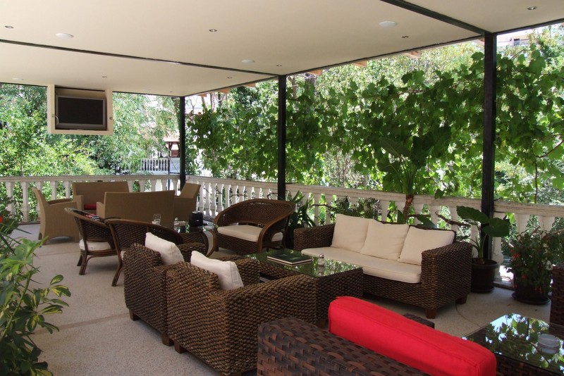 Cozy terrace with wicker furniture and a view of greenery at the Bečići hotel, Montenegro. Spacious balcony for relaxation.