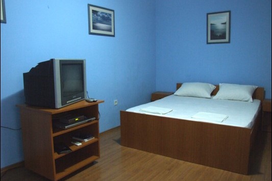 Bedroom in Hotel Bečići, Montenegro: double bed, TV on a nightstand, blue walls, and laminate flooring.