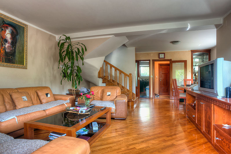 Living room in a hotel in Bečići, Montenegro: leather furniture, wooden floor, staircase, and dining area in the interior.