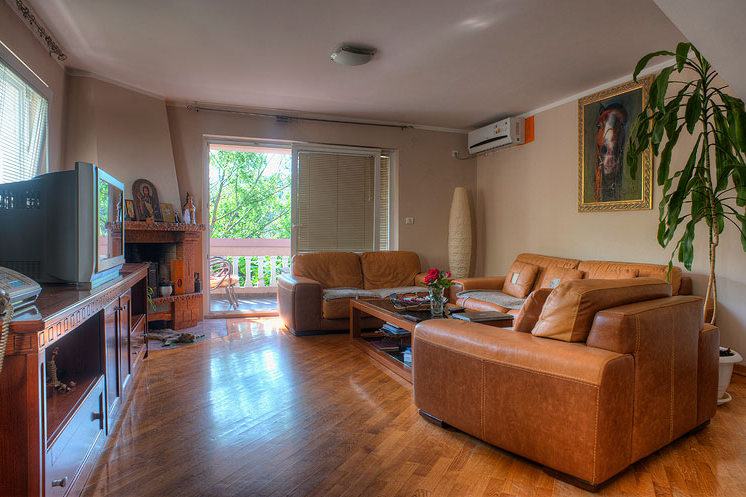 Living room with leather furniture, a fireplace, and access to the balcony in a hotel in Bečići, Montenegro. Interior with parquet flooring.