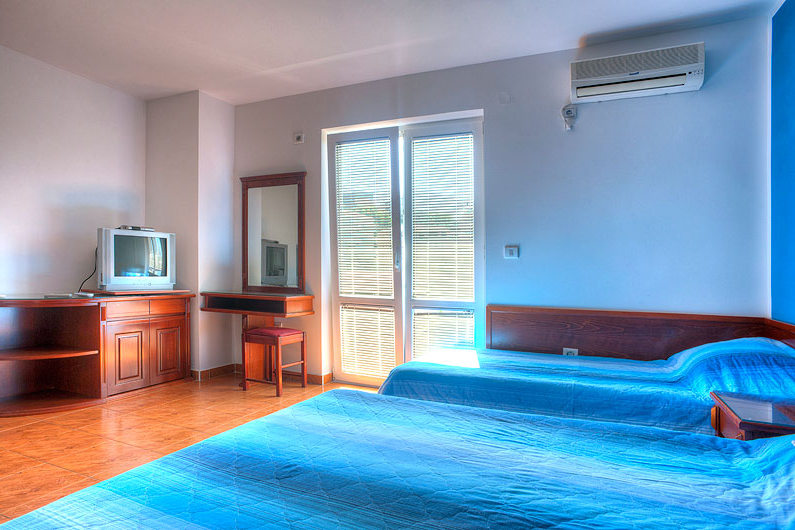 Bedroom in a hotel in Bečići, Montenegro: two beds, wooden furniture, a vanity table with mirror, and air conditioning.