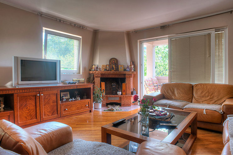 Living room with a fireplace, leather furniture, and access to the terrace at a hotel in Becici, Montenegro. Cozy interior with parquet flooring.