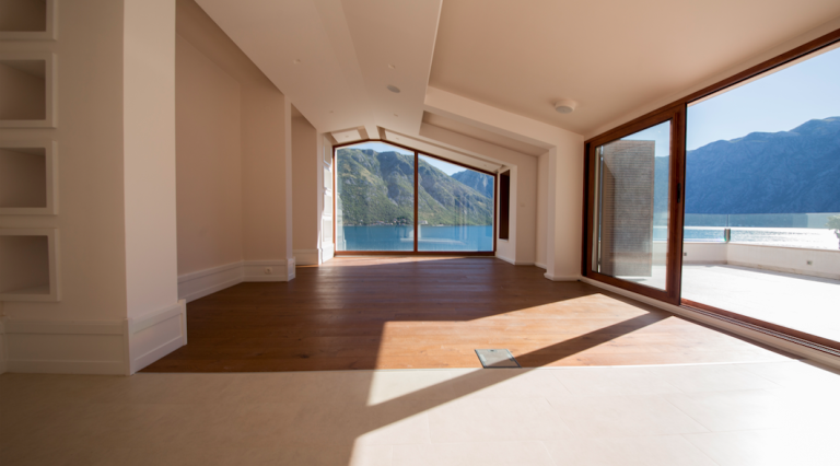 Spacious living room with panoramic views of the Bay of Kotor, Montenegro, wooden flooring, and access to the terrace.