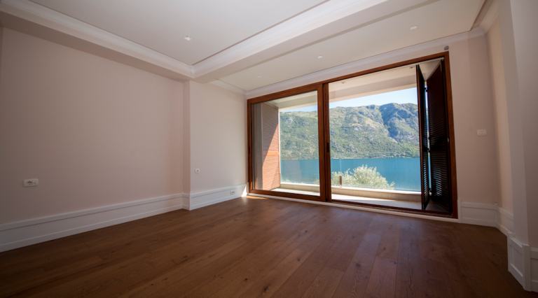 Bright living room with wooden flooring and panoramic views of the sea and mountains in a house, Stoliv, Montenegro.