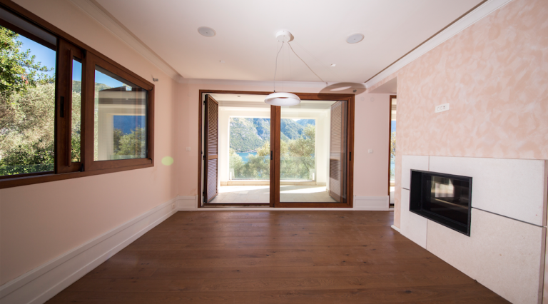 Living room in a house in Stoliv, Montenegro: panoramic view of the Bay of Kotor, fireplace, and wooden floor.