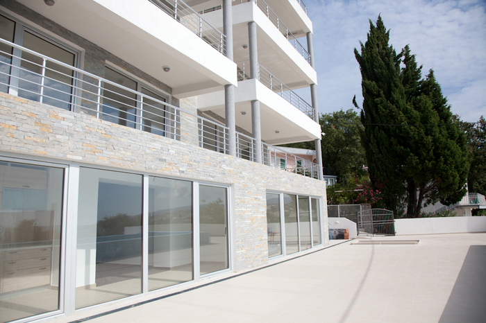 Modern residential complex with panoramic windows and a terrace in Dobrye Vody, Montenegro. The facade is finished with natural stone.