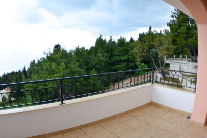 Open balcony with wrought-iron railing and a view of the pine forest in a house, Shushan, Montenegro.