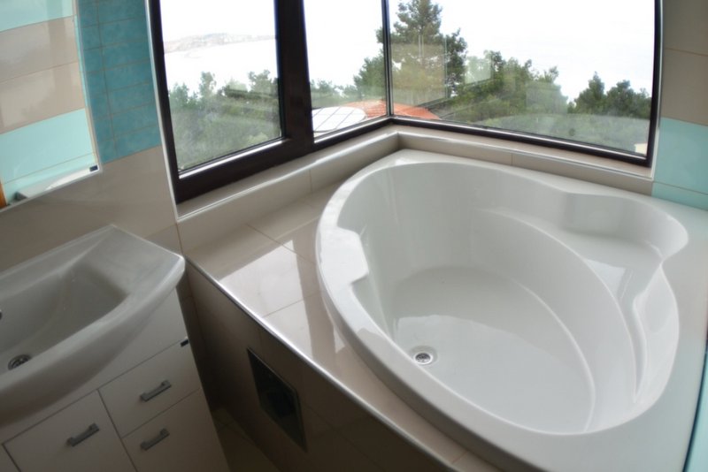 Bathroom with a corner bathtub and panoramic sea view in a house, Šušanj, Montenegro.