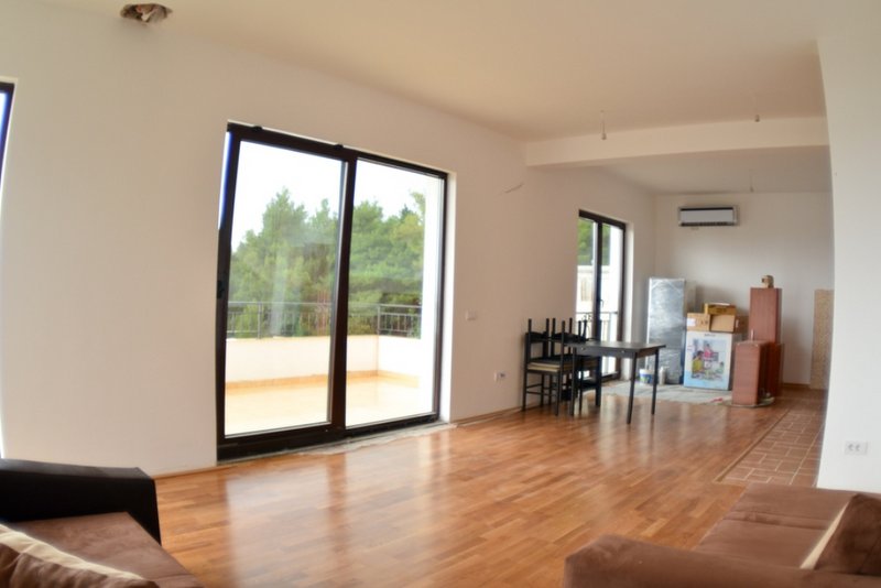 Bright living room in a house in Shushan, Montenegro: panoramic windows, access to the terrace, parquet flooring, and furniture.