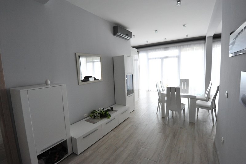 Bright living room with white furniture and dining area in an apartment, Dobri Vody, Montenegro. Modern interior with a panoramic view.