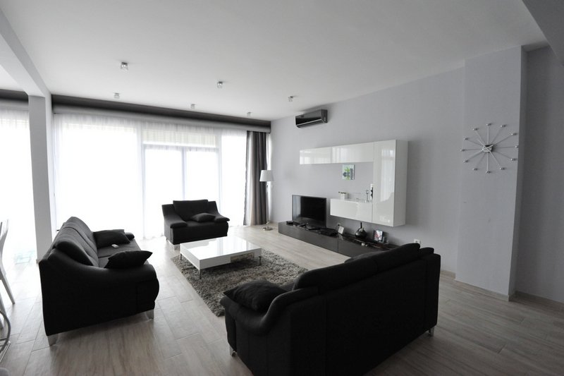 Modern living room with black sofas and panoramic windows in an apartment, Dobri Vody, Montenegro.