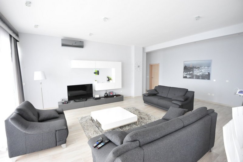 Modern living room in an apartment, Dobri Vody, Montenegro: gray sofas, a white coffee table, and a TV area.