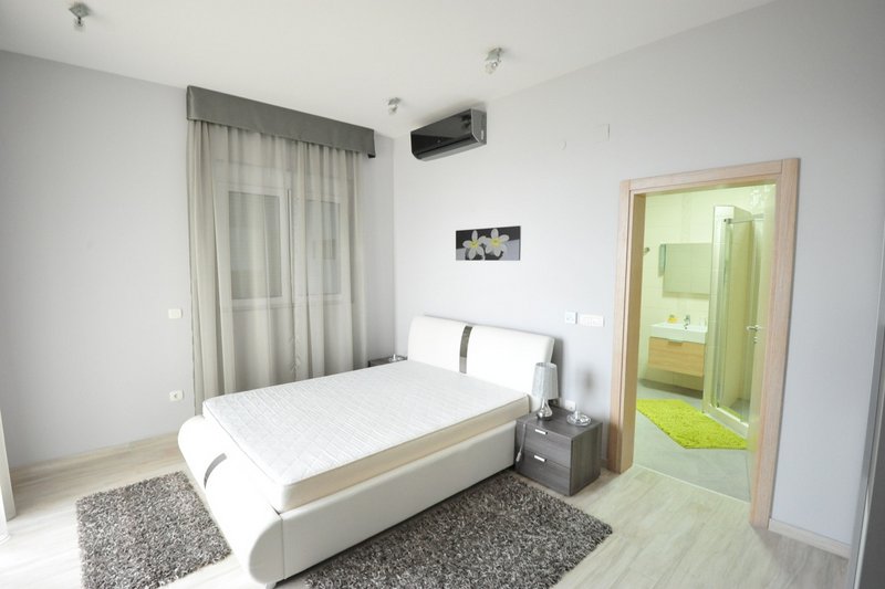 Modern bedroom with a white bed and en-suite bathroom in an apartment, Dobri Vody, Montenegro.