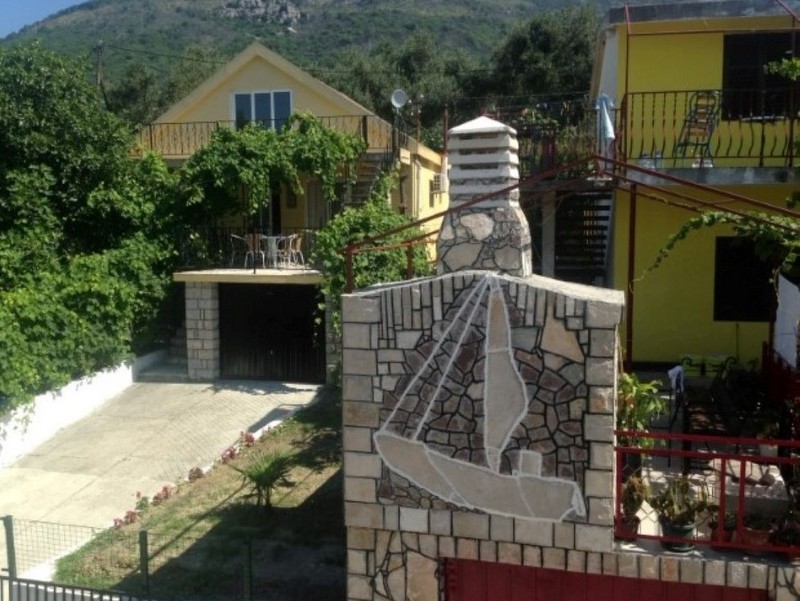 Two-story house in Shushan, Montenegro, with a stone barbecue, terrace, and mountain views surrounded by greenery.