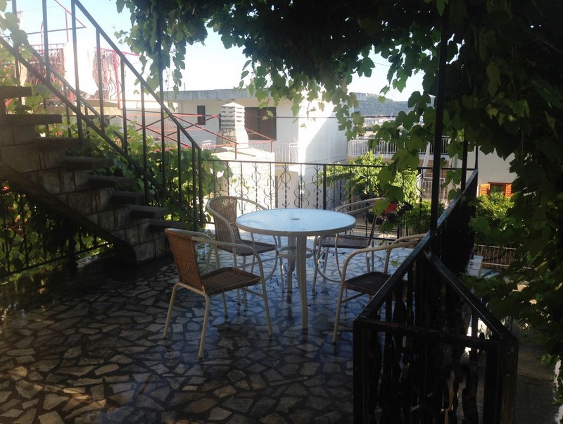 Cozy terrace with wicker chairs and a view of the garden in a house in Shushan, Montenegro. Stone floor finish and staircase.