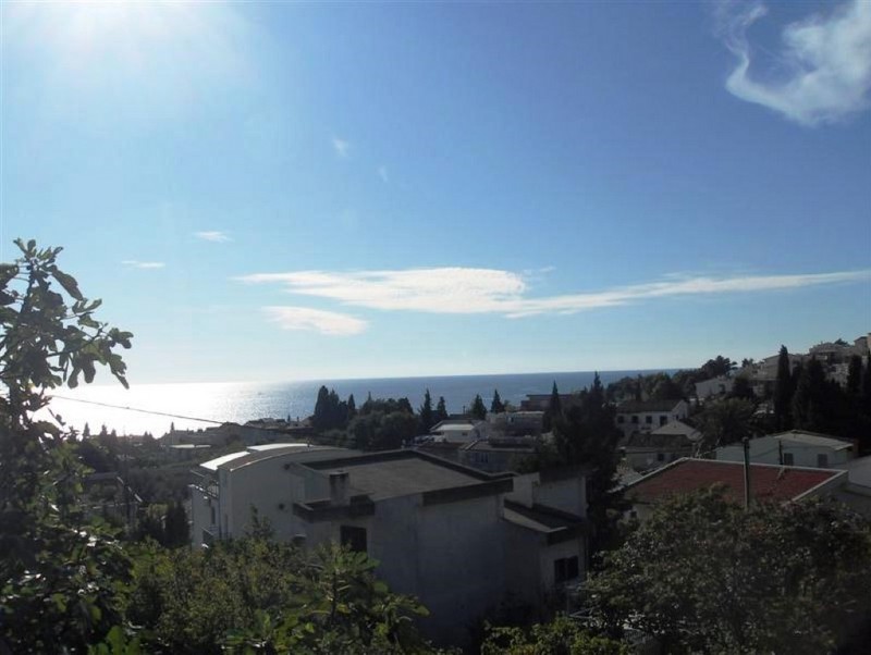 Panoramic view of the sea and the city of Šušanj in Montenegro from the house terrace, surrounded by greenery and Mediterranean trees.