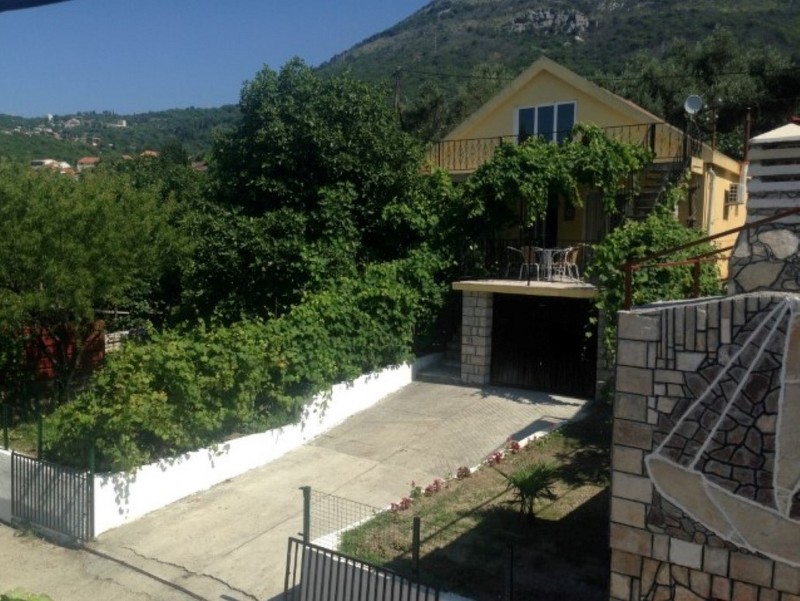 Two-story house in Shushan, Montenegro: facade with a terrace, vineyard, garage, and mountain view.