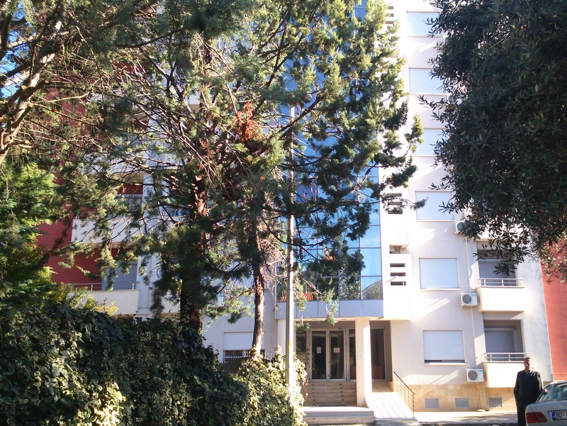 Modern residential building with panoramic glazing and a green garden in Budva, Montenegro — view of the building facade.