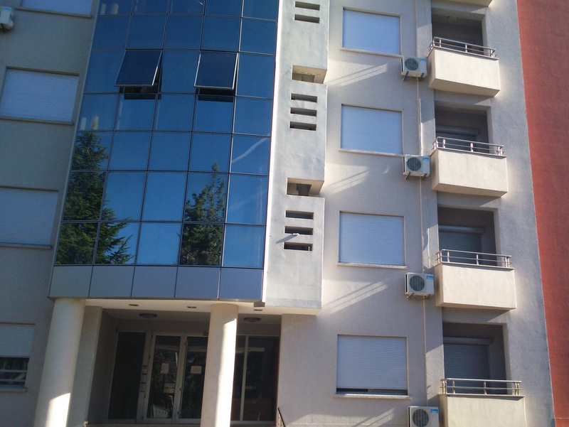 Facade of a modern residential building in Budva, Montenegro: panoramic glazing, balconies, and outdoor air conditioning units.