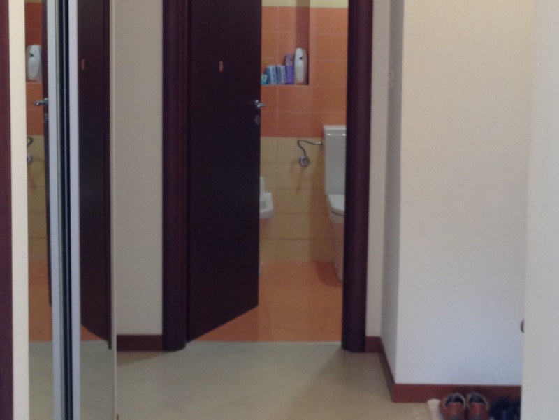 View from the hallway into the bathroom with orange tiles in an apartment in Budva, Montenegro.