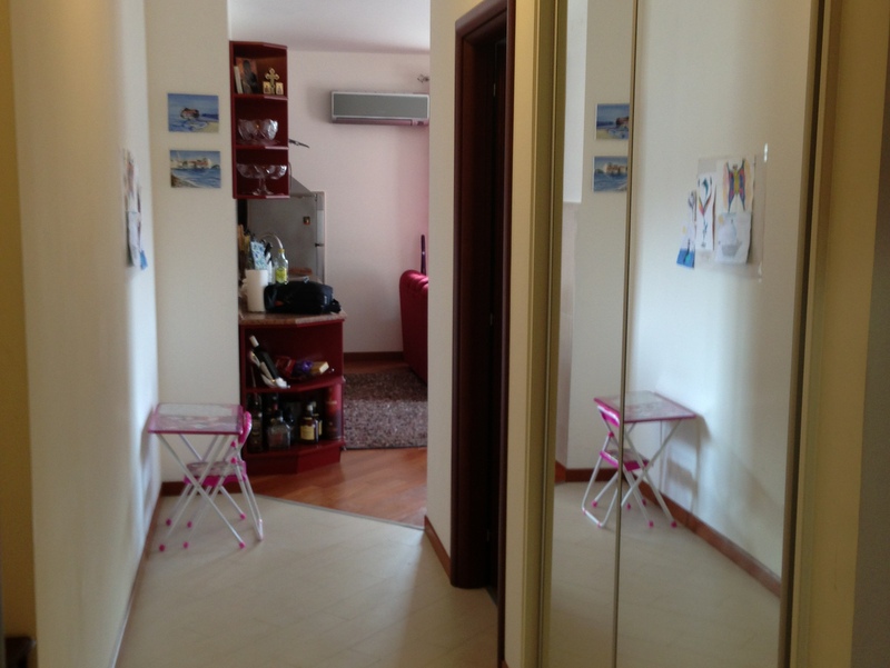 Hallway with a mirrored sliding wardrobe in an apartment in Budva, Montenegro: view of the living room with parquet flooring and air conditioning.