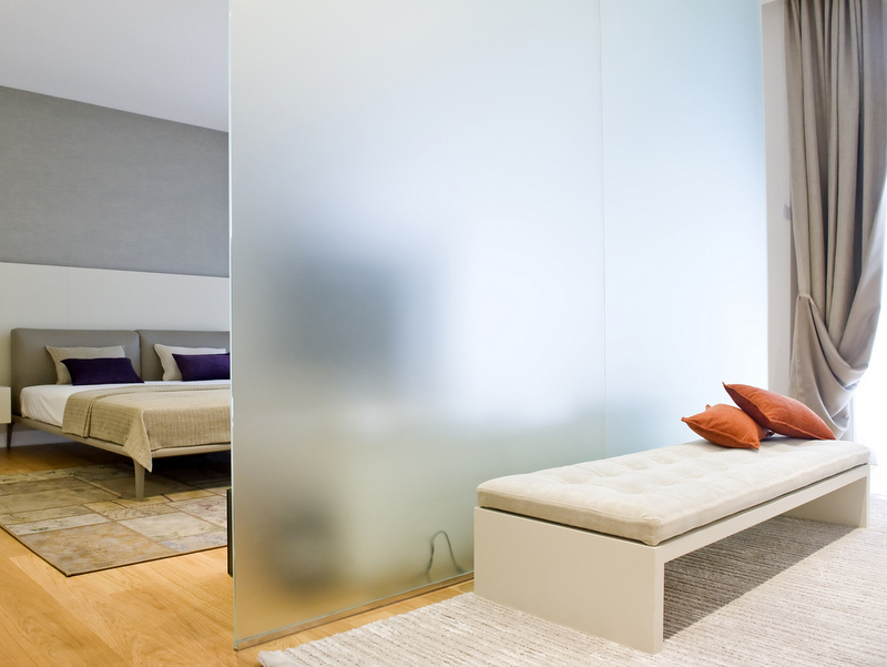 Modern bedroom with a frosted glass partition and a soft bench in Dukley apartments, Bečići, Montenegro.
