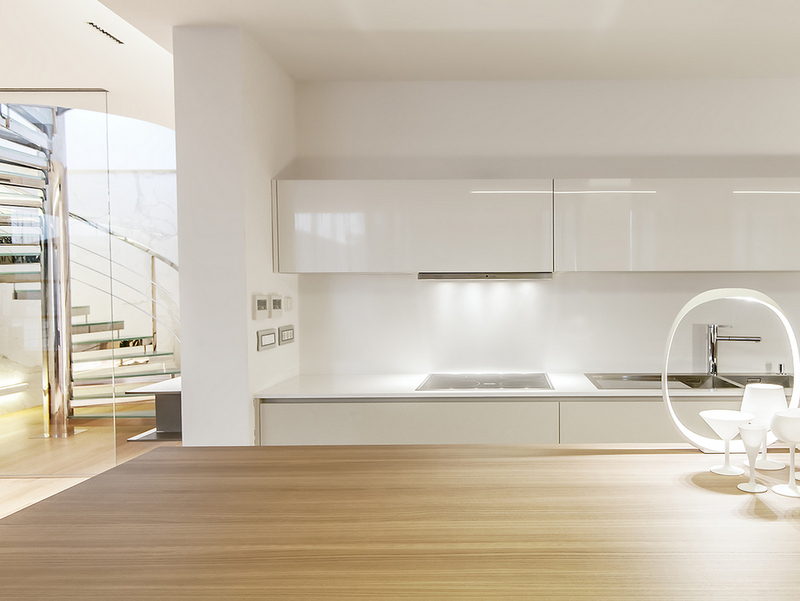 Modern kitchen in a Dukley apartment, Bečići, Montenegro: white glossy cabinets, wooden countertop, and a spiral staircase.