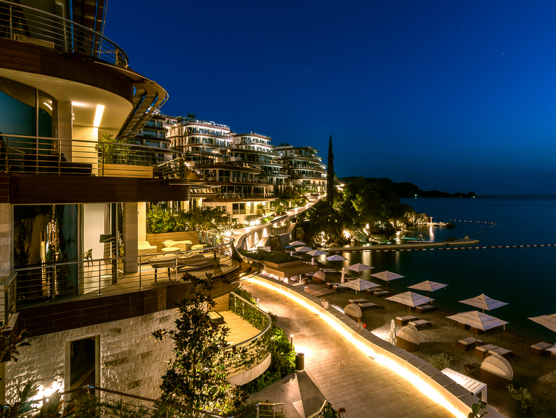 Evening view of the luxury Dukley Gardens residential complex in Bečići, Montenegro, with terraces and a private beach.
