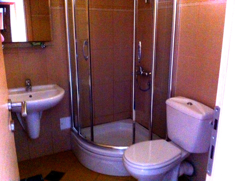 Bathroom in an apartment in Bečići, Montenegro: shower cabin, white sanitary ware, and beige wall tiles.