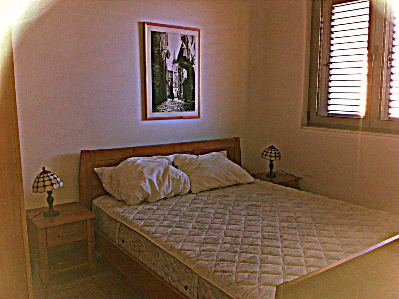 Cozy bedroom with a double bed in an apartment in Bečići, Montenegro: wooden furniture and stylish lamps.