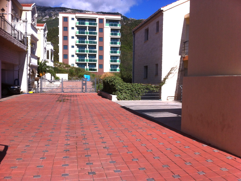 View of the courtyard area and residential complex in Bečići, Montenegro: a paved area and modern multi-story buildings.