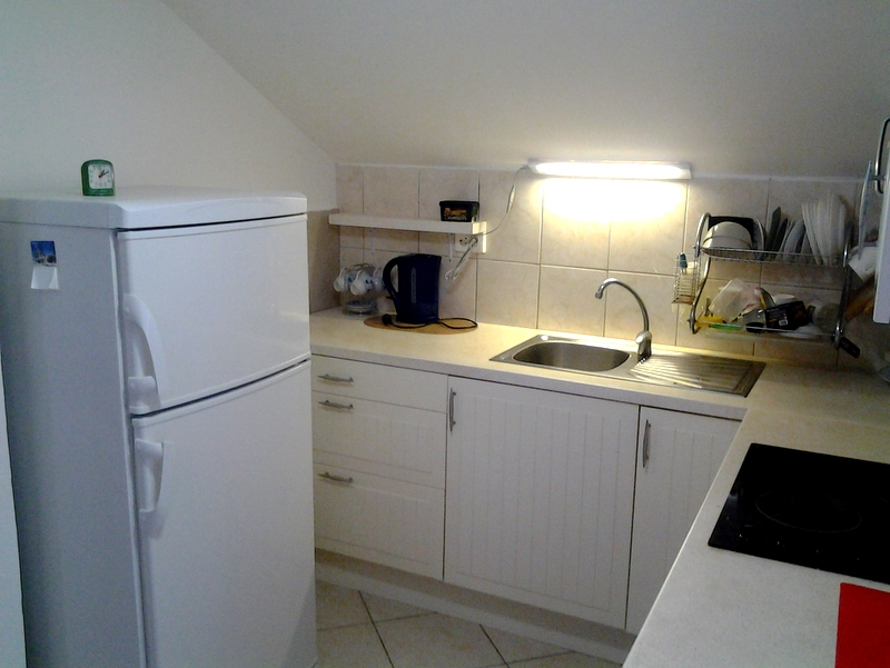 Compact kitchen in a loft apartment, Bar, Montenegro: white cabinets, refrigerator, and built-in appliances.