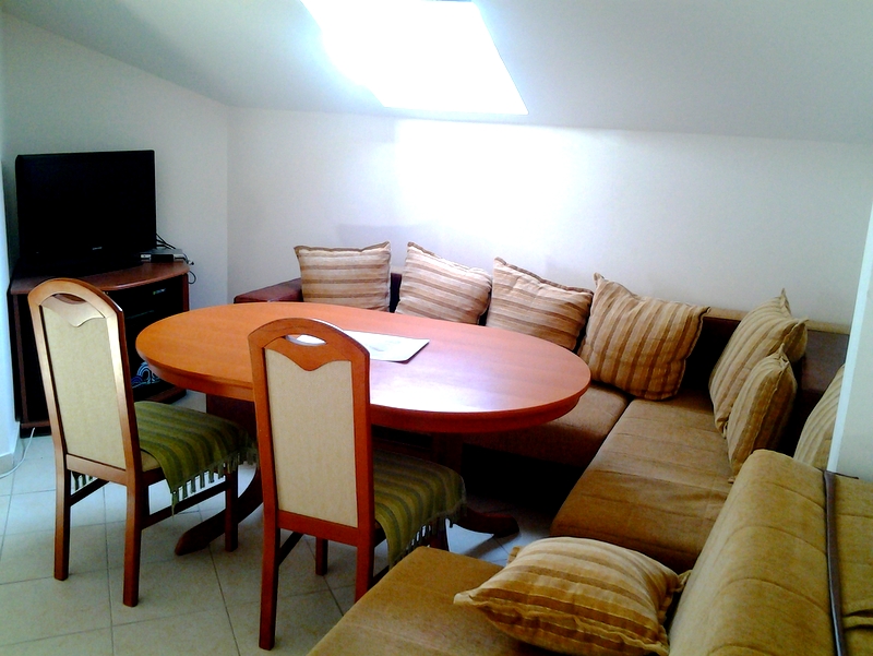 Living room in an apartment in Bar, Montenegro: dining area with an oval table, a soft corner sofa, and a skylight.