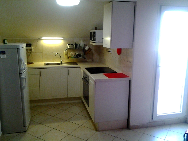 Bright kitchen in a loft apartment in Bar, Montenegro: white cabinetry, built-in appliances, and tiled flooring.