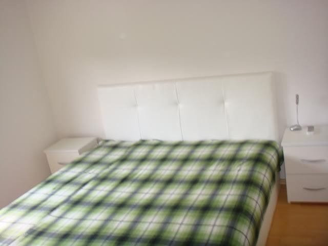 Bedroom with a white double bed and bedside tables in an apartment, Stoliv, Montenegro.