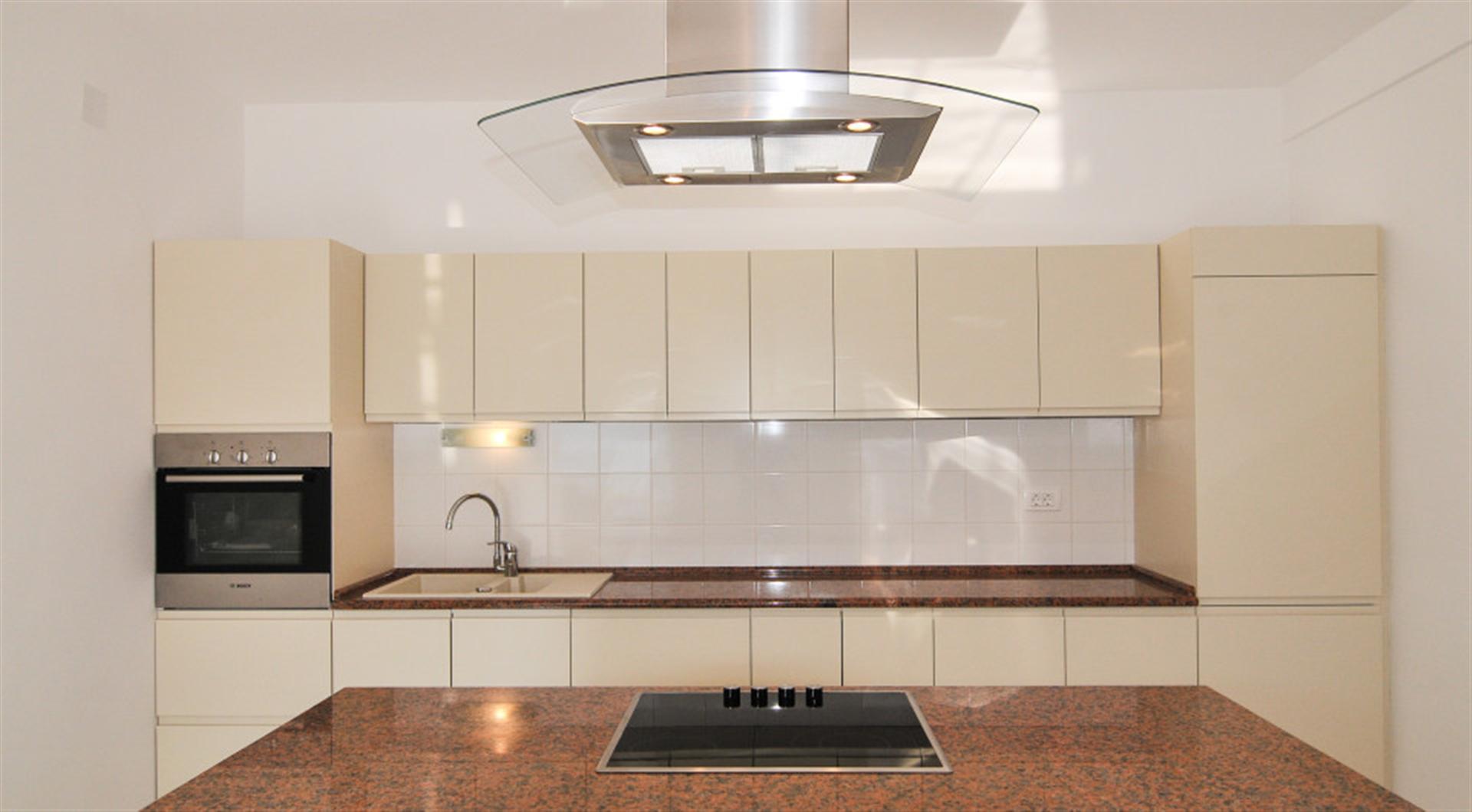 Modern kitchen with white cabinets and a granite countertop in a villa in Dražin Vrt, Montenegro.