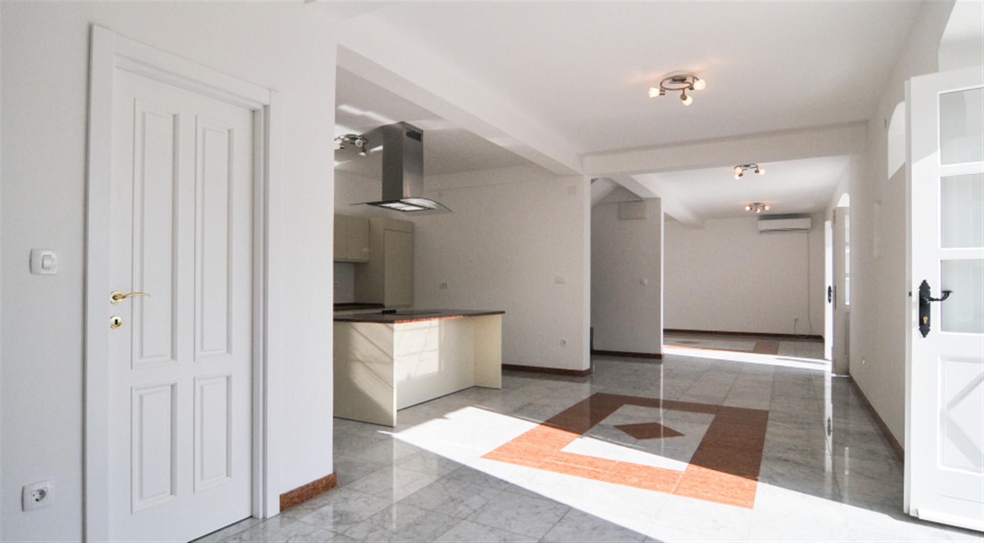 Bright living room with kitchen and marble floor in a villa in Dražin Vrt, Montenegro. Modern interior with white walls.