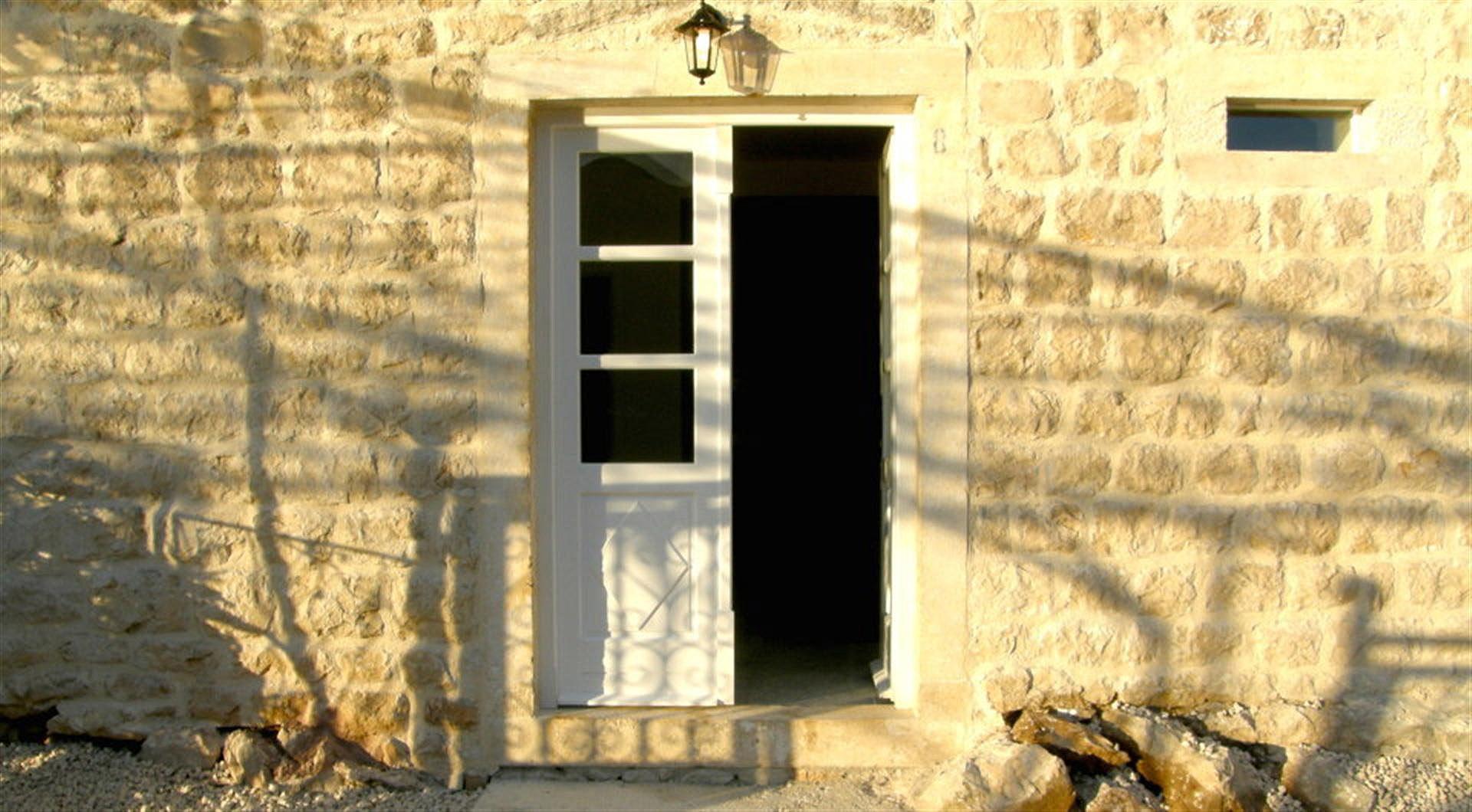 Entrance to a stone villa in Drazin Vrt, Montenegro: natural stone facade and a white wooden door.