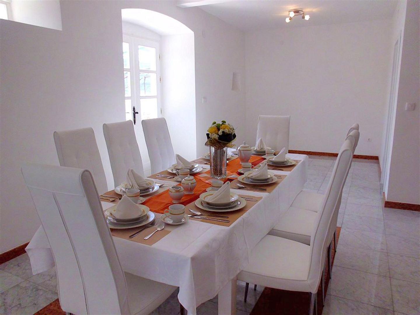 Bright dining area with a set table in a villa in Dražin Vrt, Montenegro: white furniture and tiled floor.