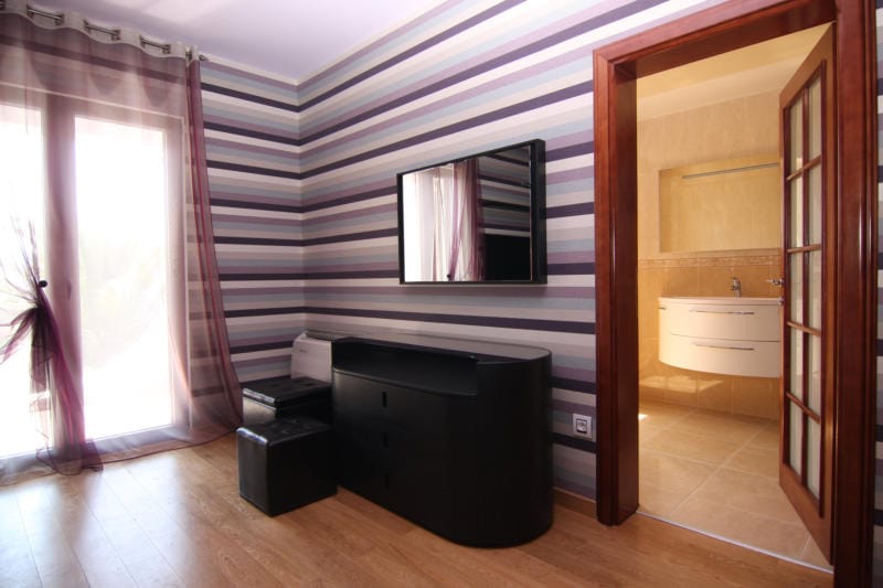 Bedroom with striped wallpaper, black furniture, and access to the bathroom in a villa in Lastva, Montenegro.