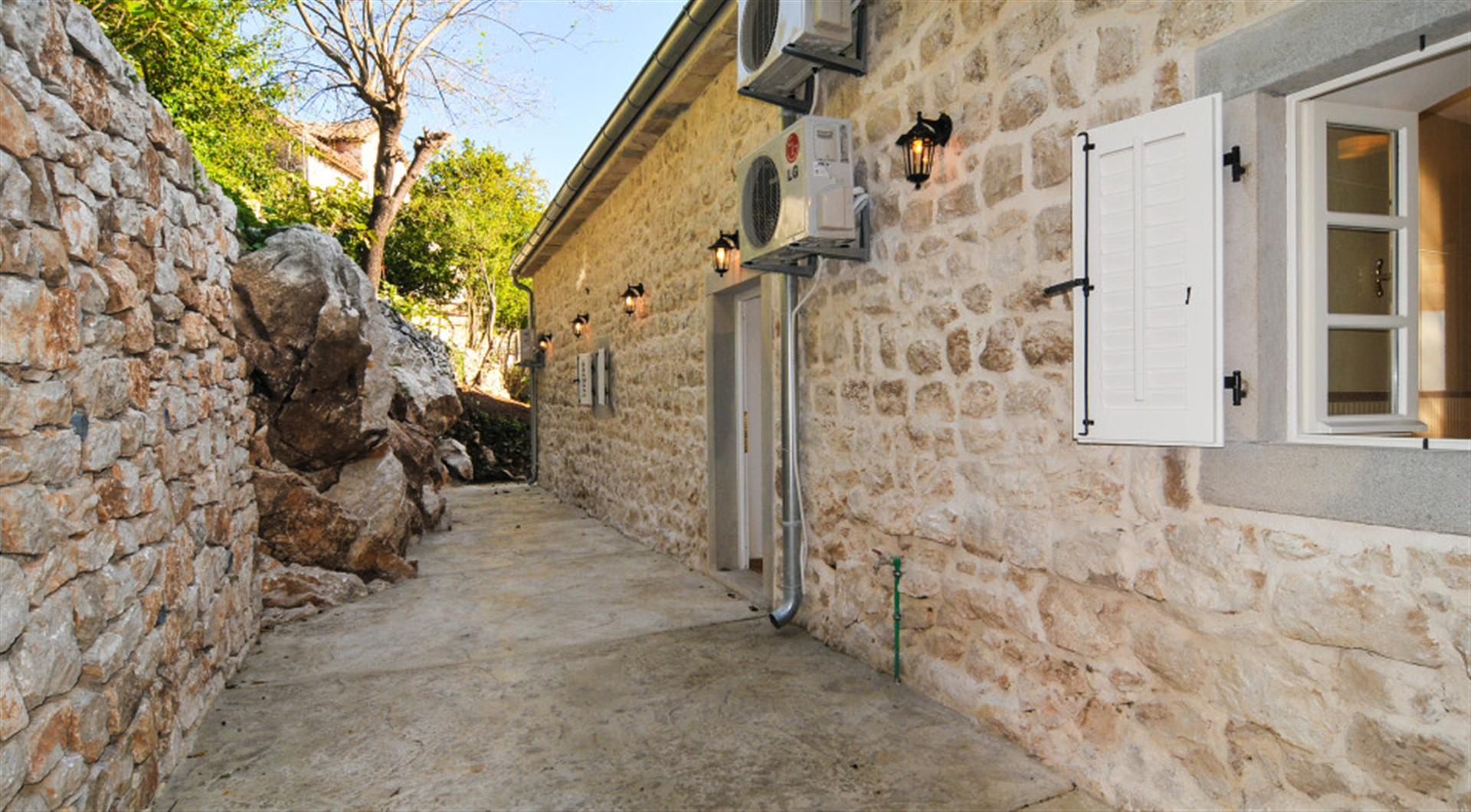 Villa facade of natural stone with a terrace in Dražin Vrt, Montenegro: view of stone walls and landscaping.