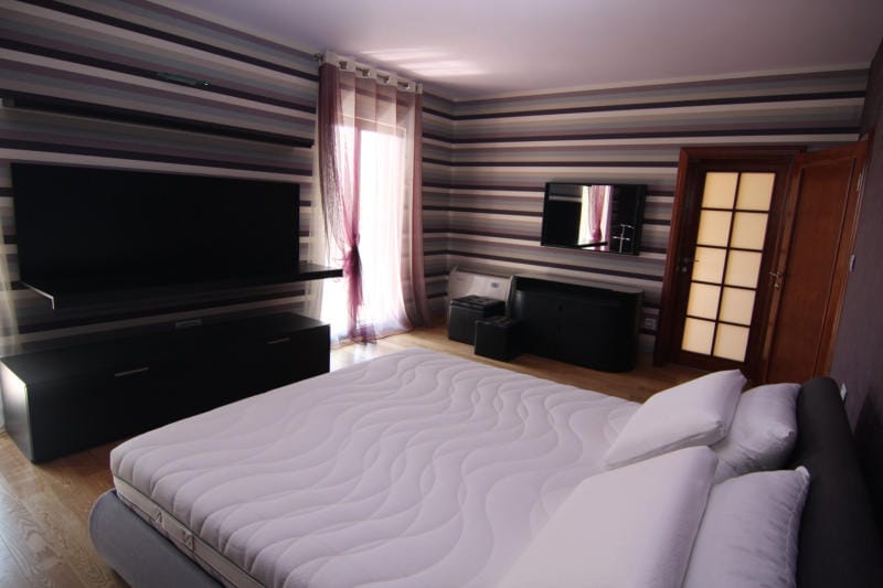Modern bedroom with a double bed and striped wallpaper in a villa in Lastva, Montenegro.