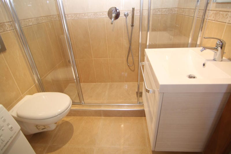 Bathroom with shower cabin and light-colored furniture in a villa in Lastva, Montenegro: modern tile finish.