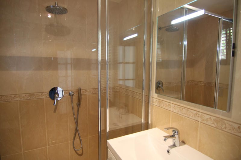 Bathroom with a shower cabin and light-colored tiles in a villa in Lastva, Montenegro. Modern fixtures and a mirror.