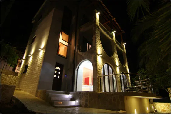 Night view of a stone building facade with lighting, arched entrance, and steps.
