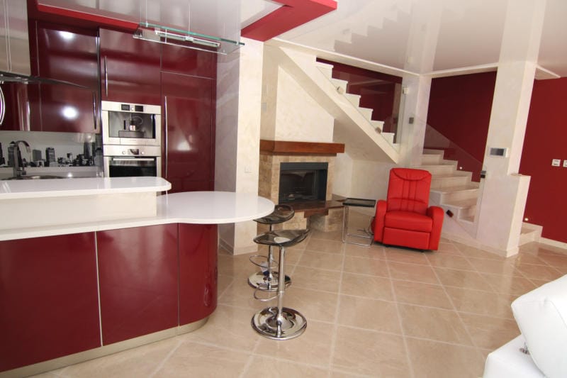 Modern kitchen-living room with a bar counter and fireplace in a villa in Lastva, Montenegro: stylish interior with a staircase.