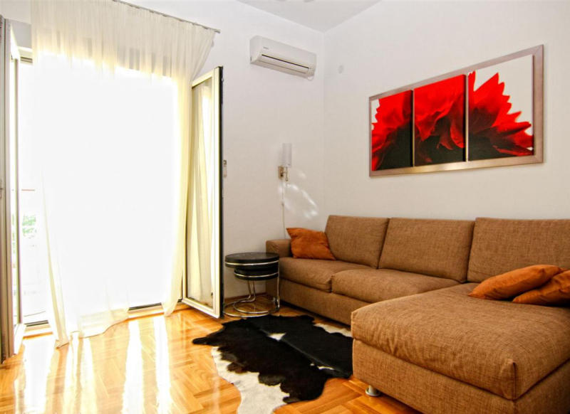 Cozy living room with a brown sofa and access to the balcony in an apartment in Bečići, Montenegro. Modern interior.